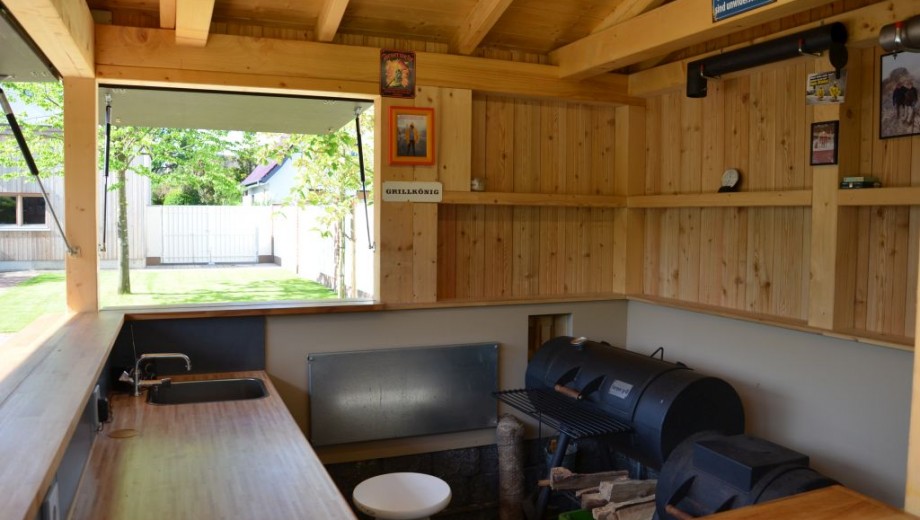 Gemütliche Outdoor-Küche mit Grill, Holzarbeitsbereich und Dekorationen, bereit für gesellige Abende.