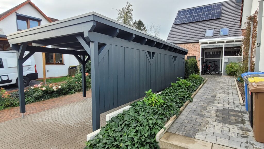 Moderner Außenbereich mit Carport, Solarpanelen, Blumenbeeten und Fahrrädern; sauber und gepflegt.