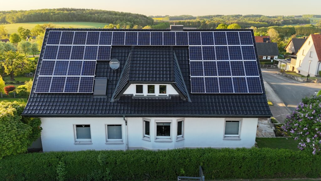 Ein Einfamilienhaus mit Solarpaneelen auf dem Dach, umgeben von einem gepflegten Garten in ruhiger Umgebung.