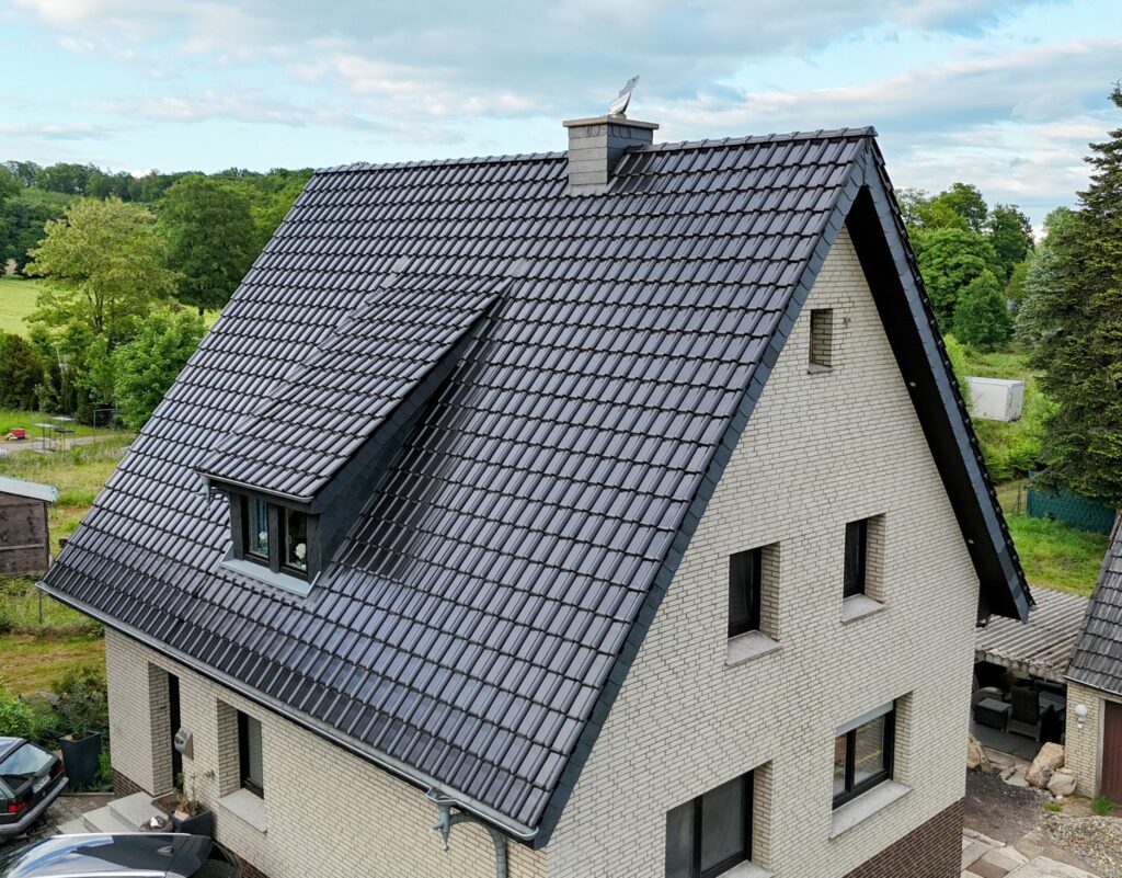 Einfamilienhaus mit steilem, dunkelgrauem Satteldach und heller Ziegelfassade in ruhiger Umgebung.
