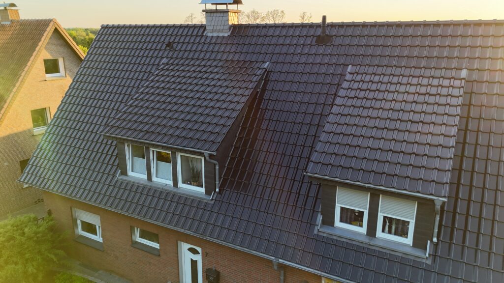 Wohnhaus mit dunklem Ziegeldach, roten Backsteinwänden und weißen Fensterrahmen bei ruhigem Licht.