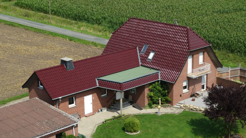 Ländliches Backsteinhaus mit rotem Ziegeldach, gepflegtem Garten und kleinem Balkon in ruhiger Umgebung.