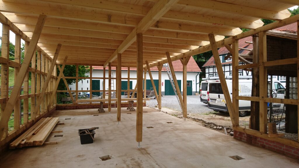Ein ruhiger Moment auf einer Baustelle mit einem Holzrahmenbau, umgeben von Gebäuden mit Ziegeldächern.