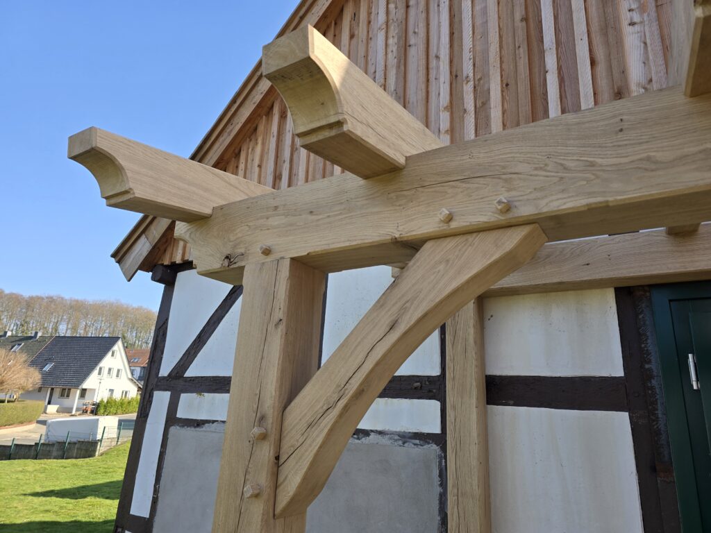 Ein traditionelles Fachwerkhaus mit hellen Holzbalken und weiß verputzten Wänden unter klarem Himmel.