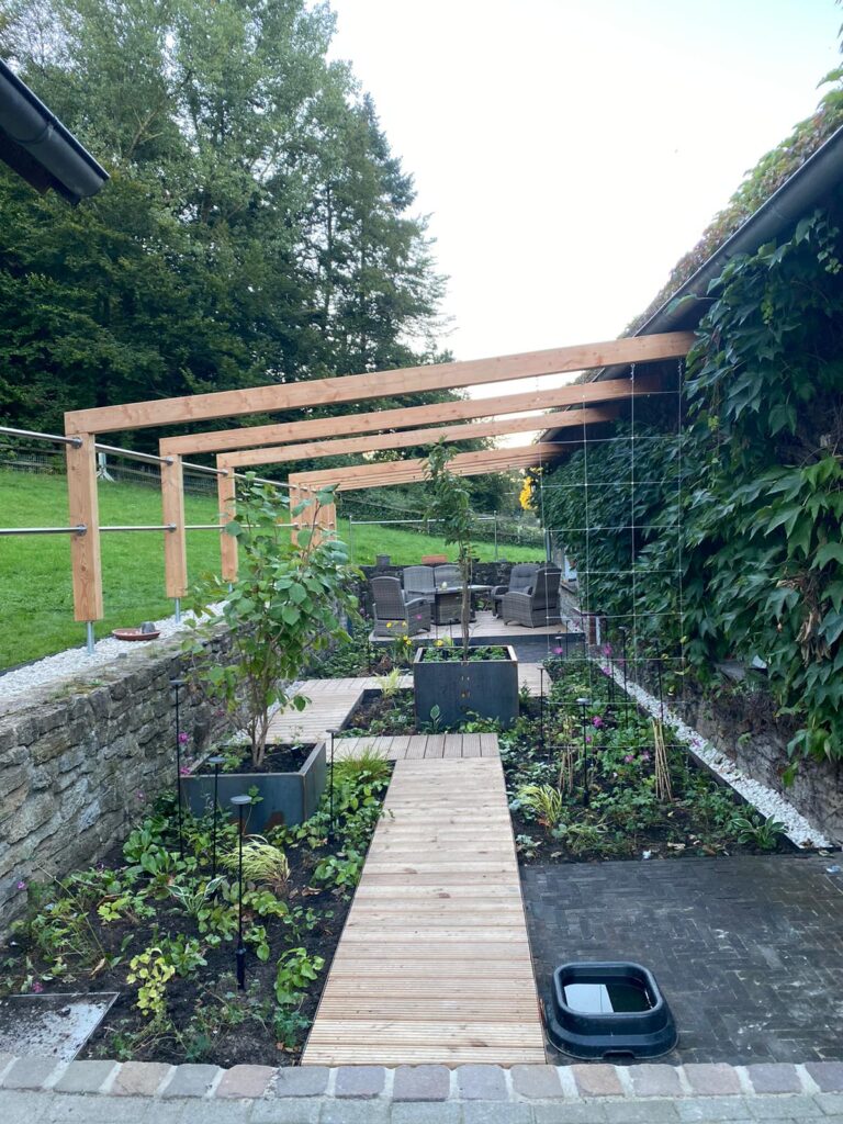 Ein gepflegter Garten mit Holzpergola, gepflastertem Weg und Sitzgruppe, umgeben von üppigem Grün.