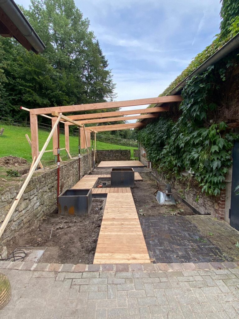 Eine Baustelle im Garten mit Holzrahmen, Pflanzkästen und einem Holzweg, umgeben von Natur.