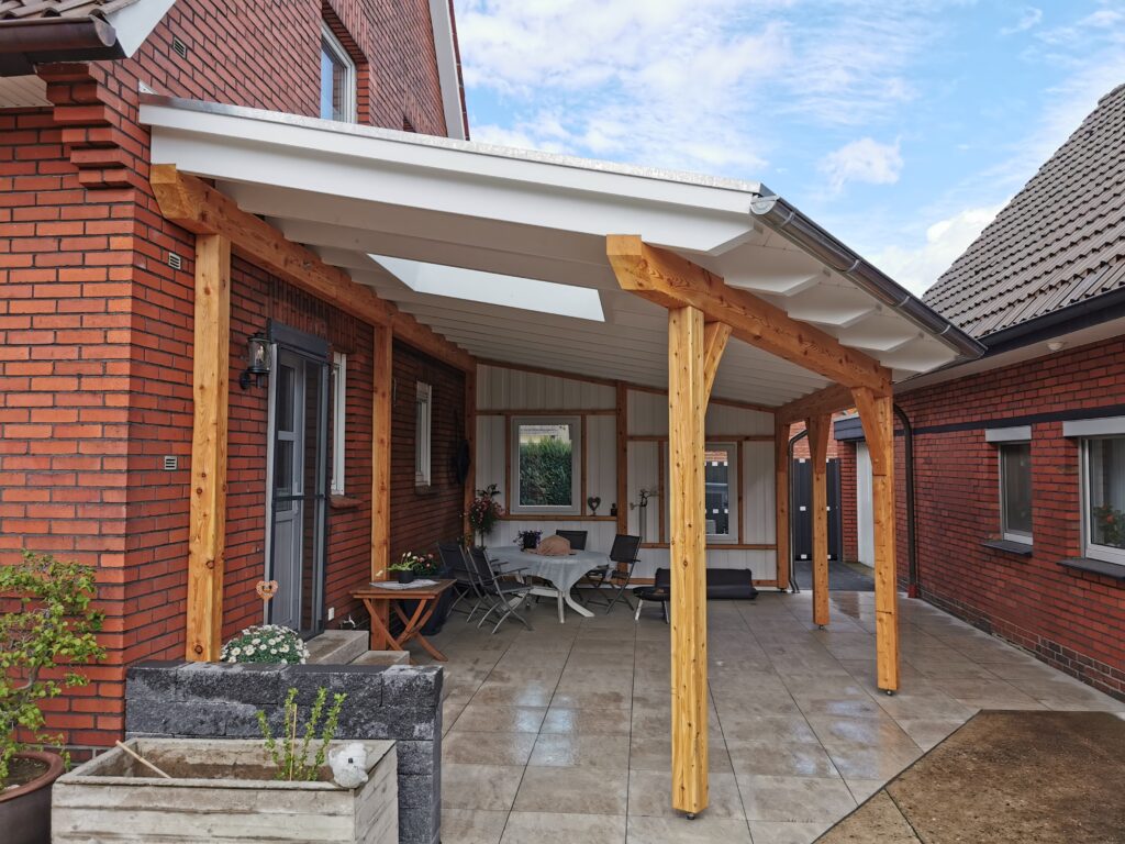 Überdachte Terrasse mit Holzdach, roten Backsteinwänden, dunklen Möbeln und Topfpflanzen.