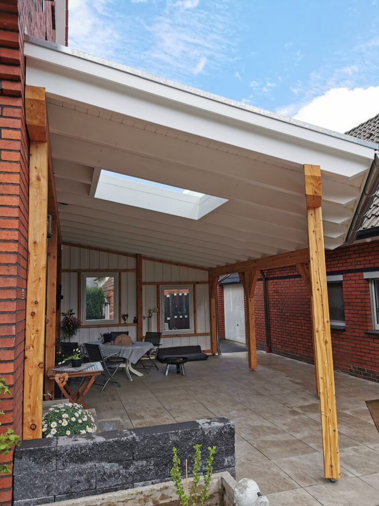 Überdachte Terrasse mit Sitzgruppe, roter Backsteinwand und natürlichem Licht durch ein Oberlicht.