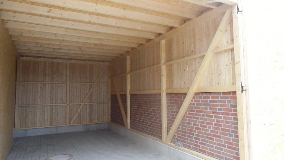 Innenansicht einer sauberen, funktionalen Garage mit Holzwänden, Ziegelsteinen und Betonboden.