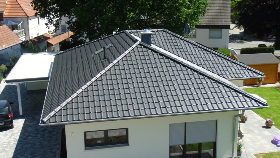 Moderne Vogelperspektive: Haus mit grauem Dach, Carport, grünem Garten und sonniger Umgebung.