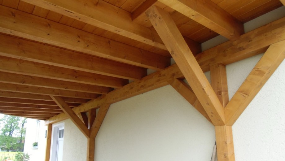 Holzüberdachung an heller Wand, warmes Braun des Holzes, schafft einladende und stabile Atmosphäre.