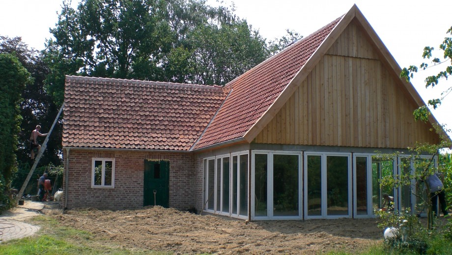 Ein Haus mit Backstein und Glas, Arbeiter renovieren, ländliche Umgebung, rote Ziegeldach.