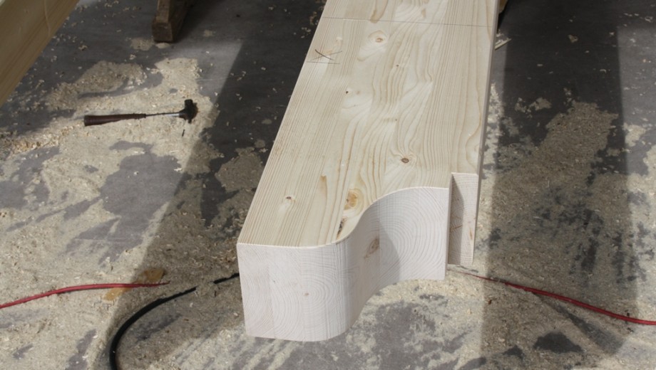 Eine Holzwerkstatt mit einem großen Holzstück, verstreuten Holzspänen und einem Hammer auf dem Boden.