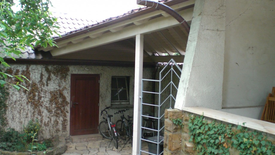 Ein ruhiger Hinterhof mit zwei abgestellten Fahrrädern, einer Holztür und Efeu an der Wand.