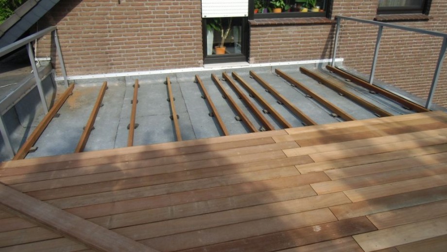 Teilweise fertiggestellte Holzterrasse auf Flachdach, mit verlegten Dielen und sichtbarer Unterkonstruktion.