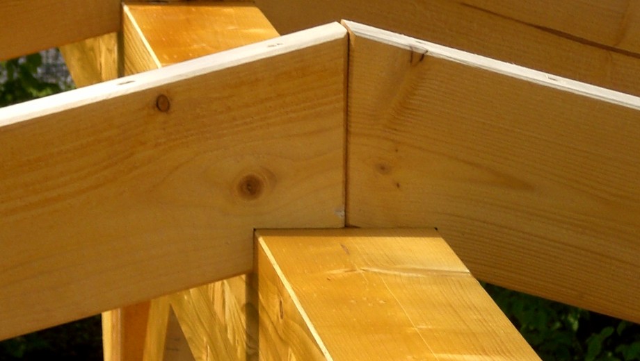 Nahaufnahme eines präzise verbundenen Holzverbindungsstücks in einer Holzkonstruktion, vermutlich Dachstuhl.