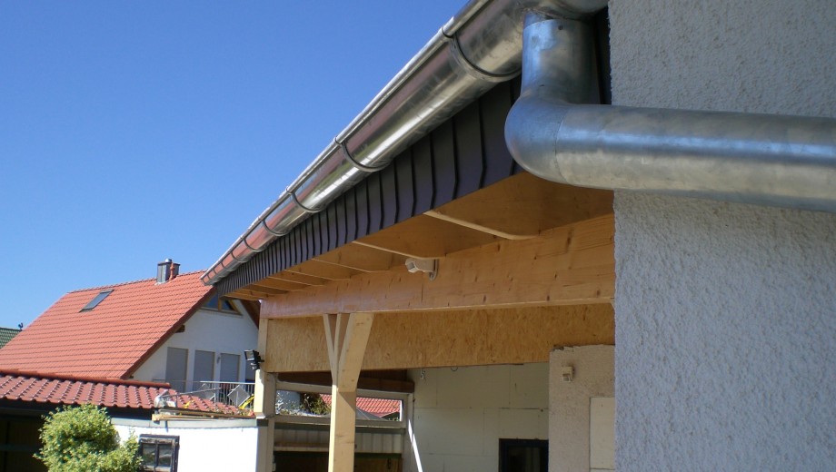 Ein Gebäude mit rotem Ziegeldach, silberner Dachrinne und blauem Himmel im Hintergrund.